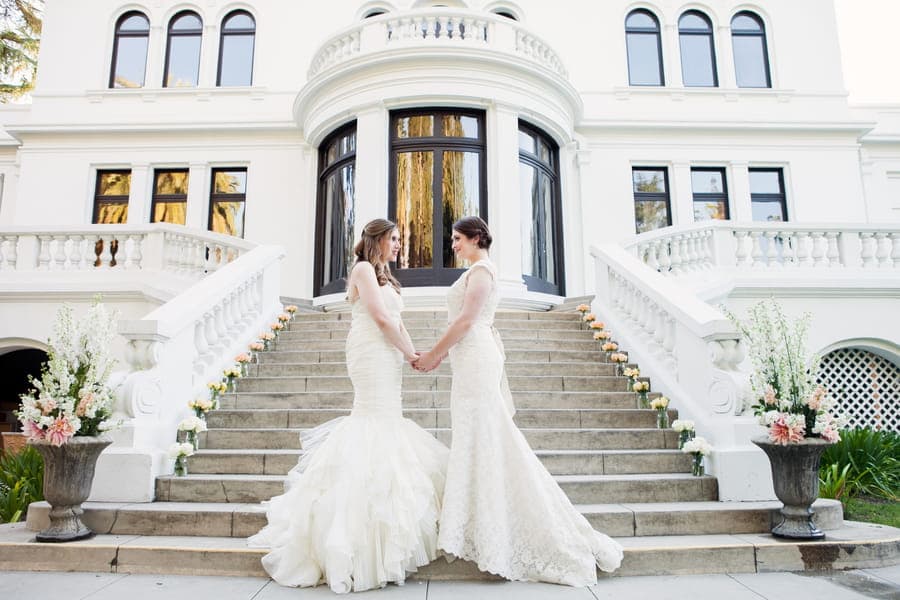 O que é o casamento gay? Casal de noivas, de mãos dadas, e vestidas de branco em frente (Foto: Michele Lascon Photography)