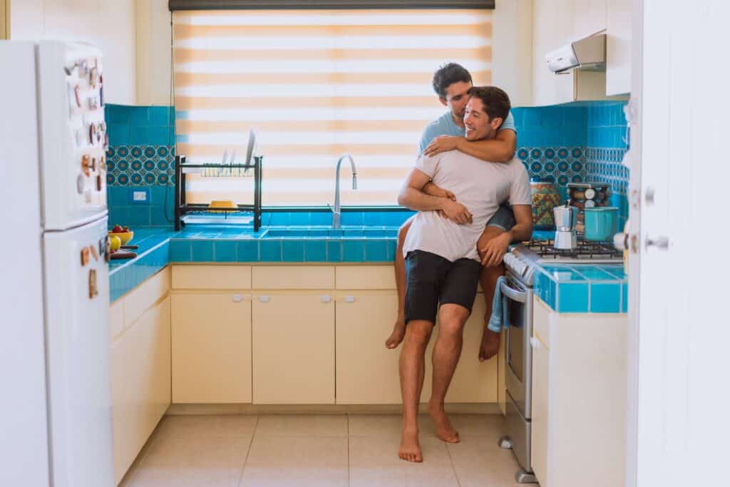 Casal de homens gays na cozinha se abrançando (Foto: Los Muertos Crew/Pexels)